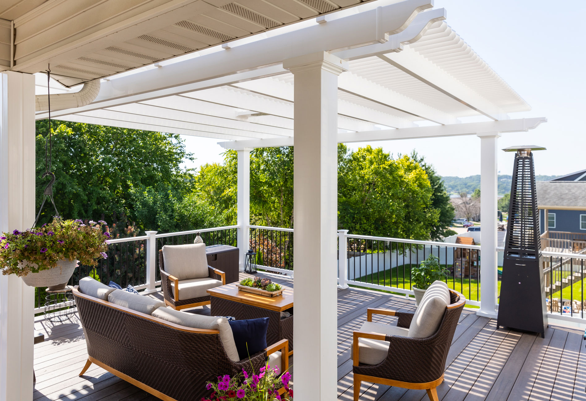 Comfy outdoor furniture on a deck under a large white pergola