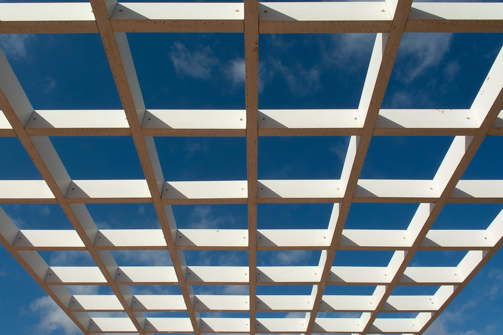 An open pergola roof grid with clear view of the blue sky