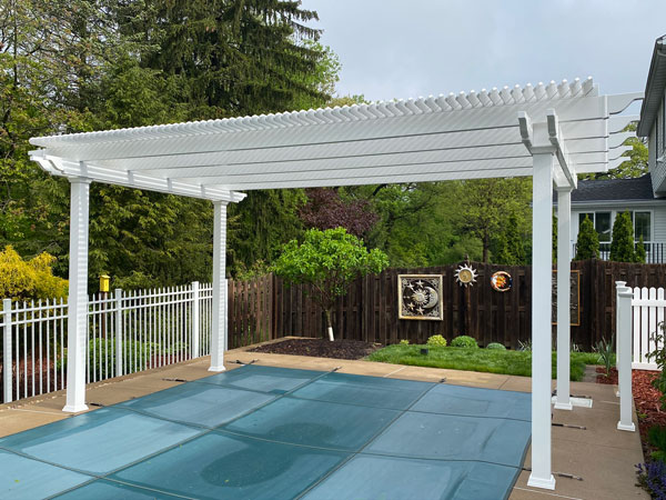 A pergola cover over a pool built with a white vinyl pergola to create shade over the pool