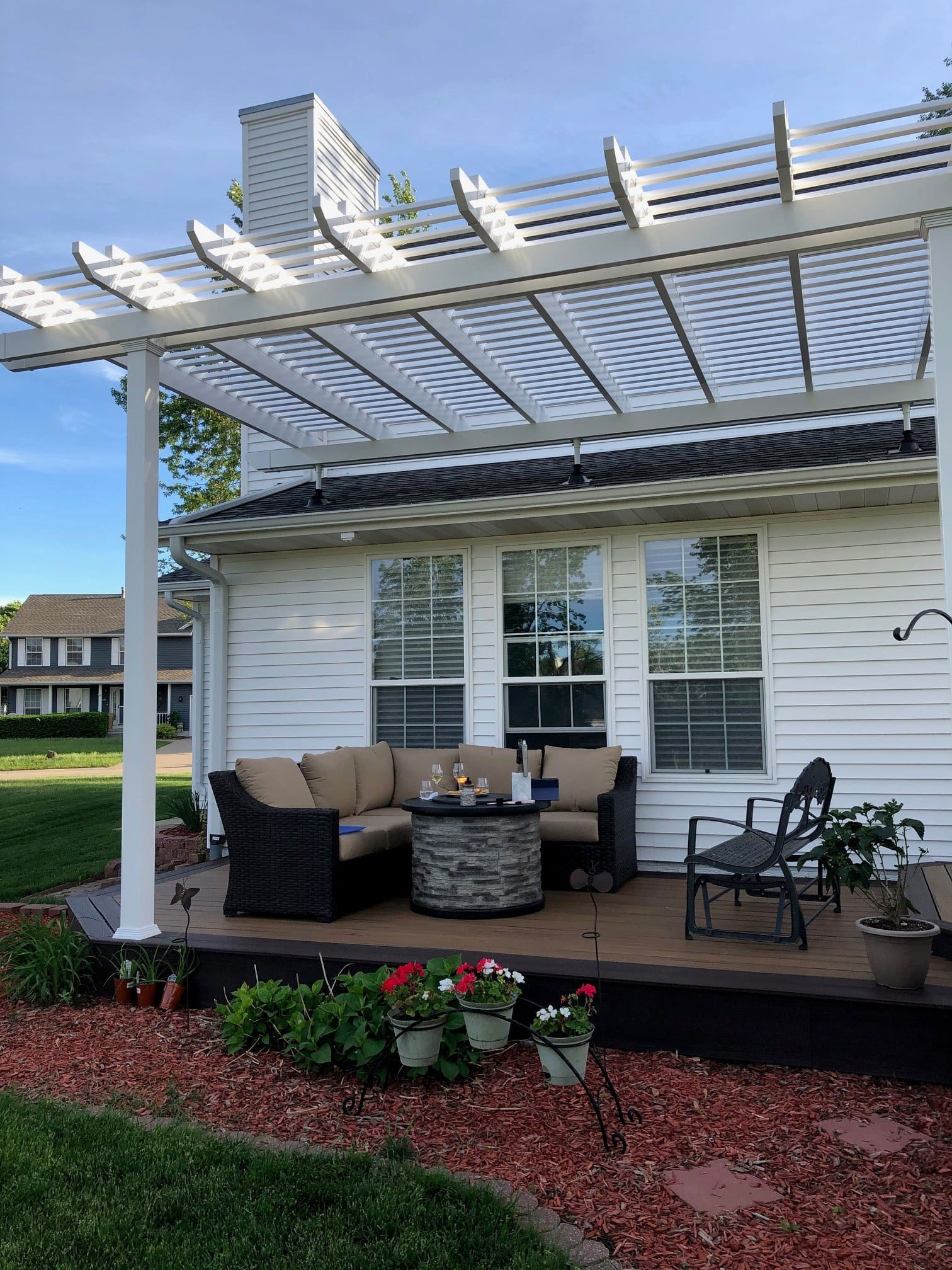 White pergola on patio with roof riser attachment to the home