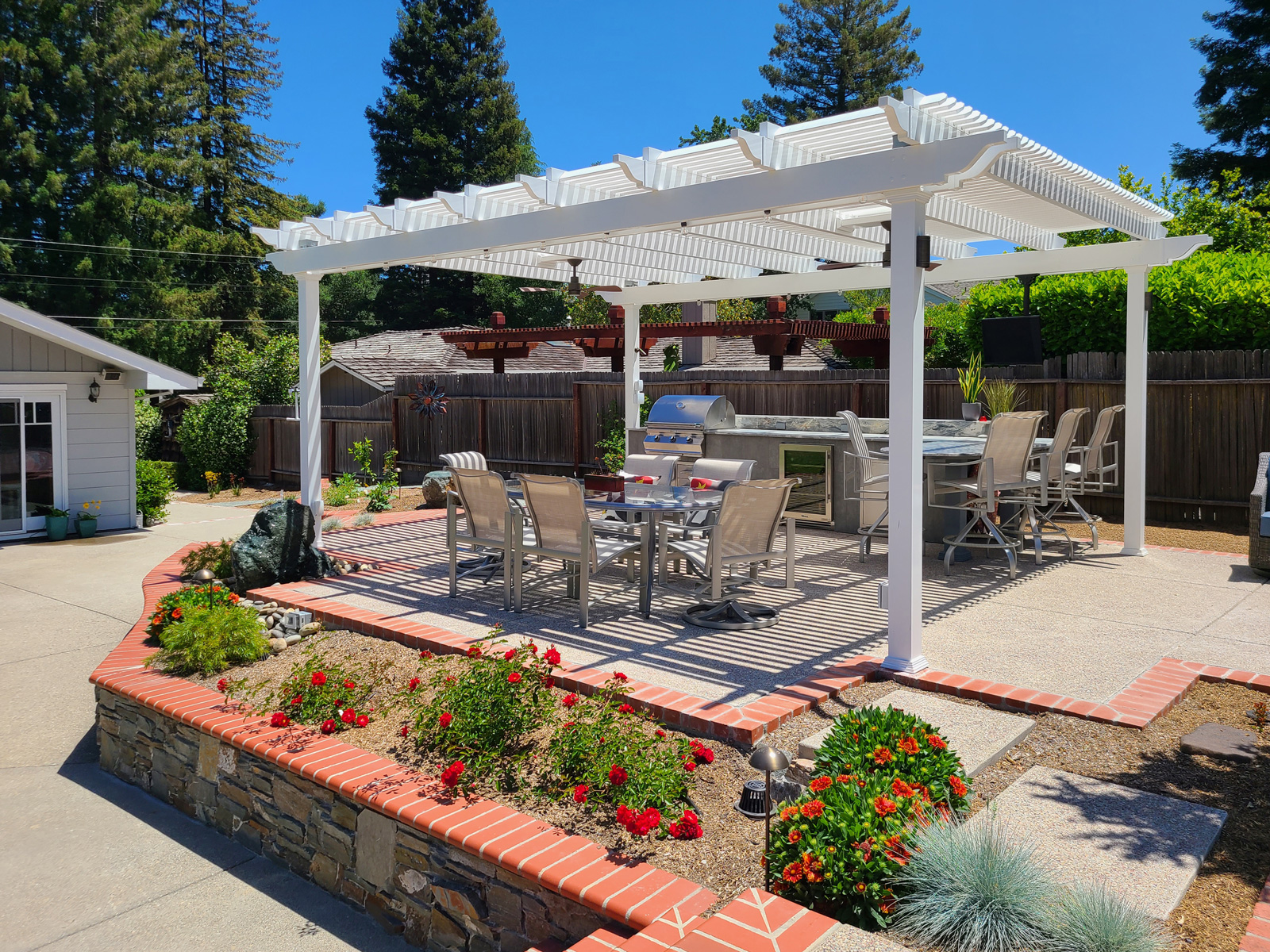 free standing pergola over a raised patio outdoor kitchen and dining area.