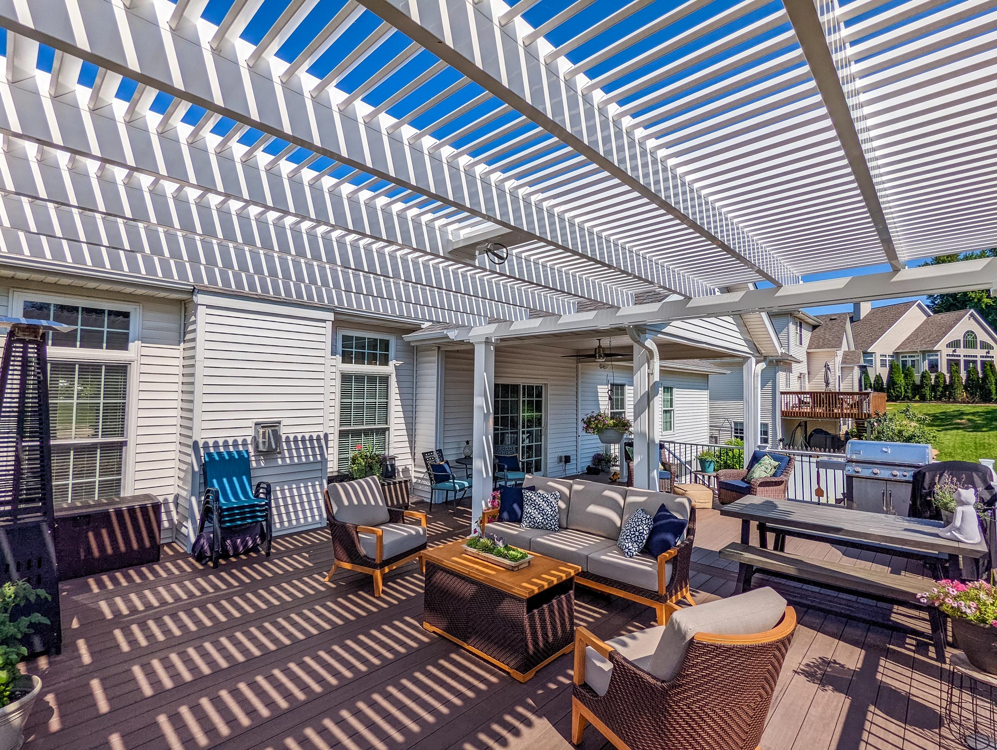 white pergola with 75% shade over a deck with outdoor furniture and fire table