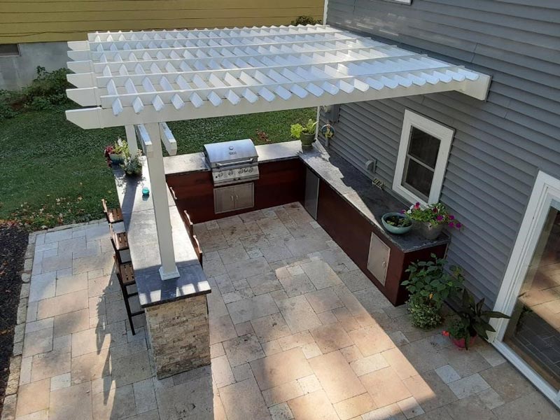 an attached patio pergola with posts ontop of an outdoor kitchen countertop.