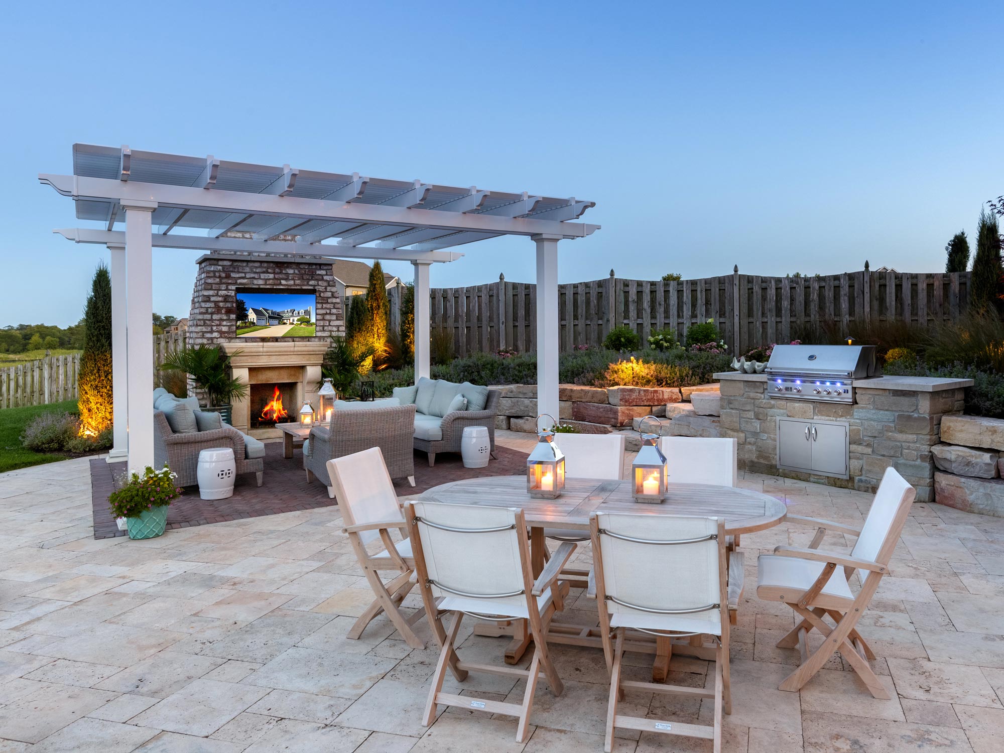 free standing pergola on a stone patio with outdoor fireplace, grill and dining area