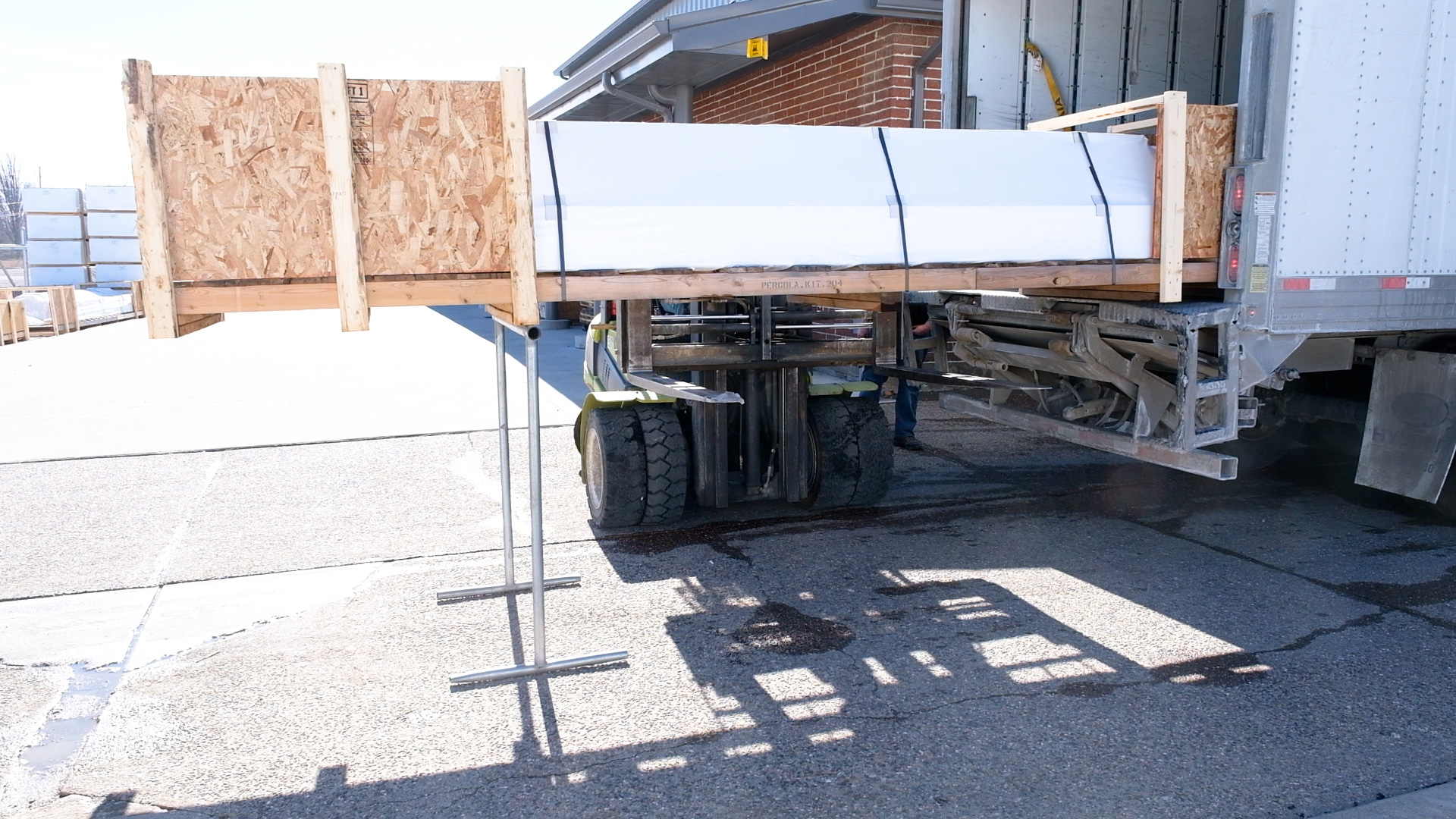 pergola pieces are on a pallet wrapped in boat wrap with a forklift truck moving the pallet