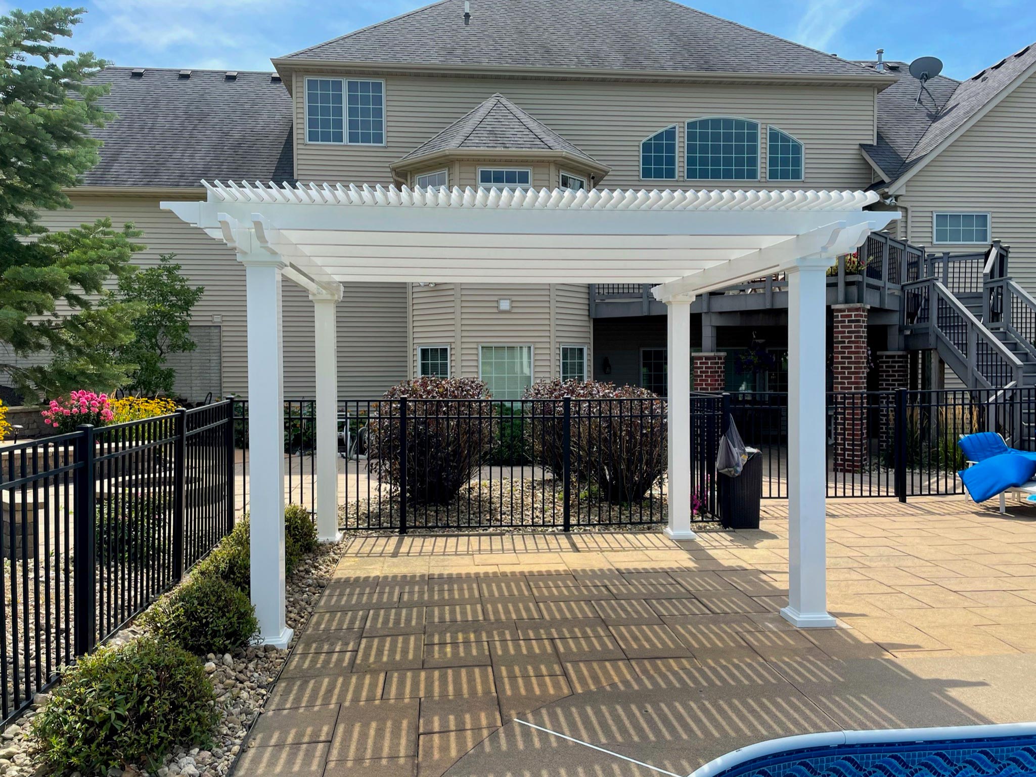 Vinyl pergola kit constructed over a pool side patio creating shade below
