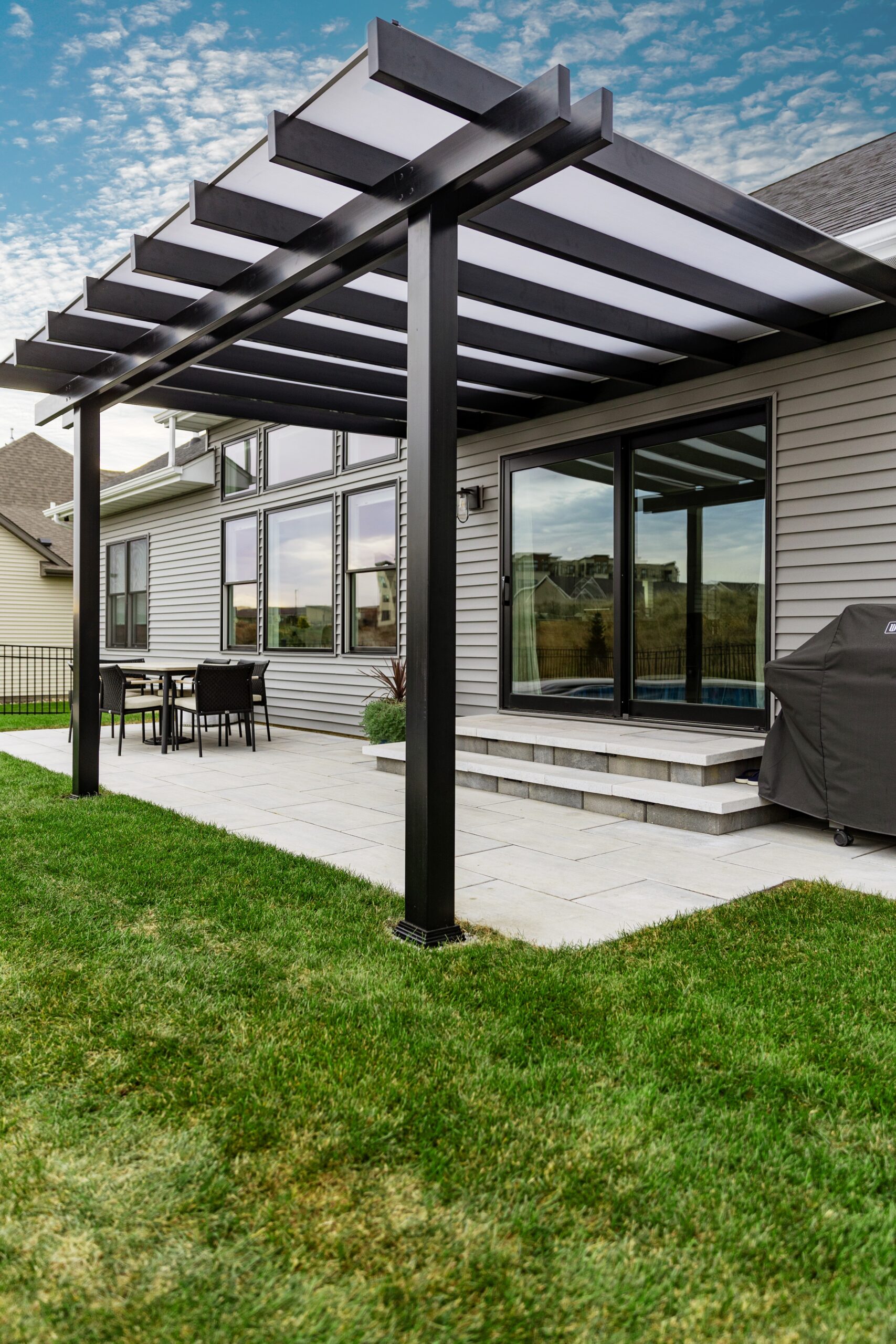 Black patio cover with white polycarbonate roof over a patio