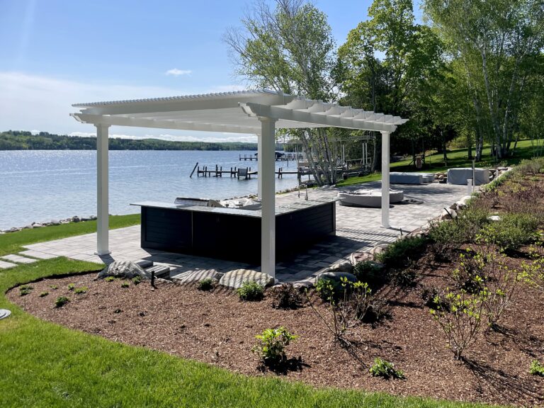 Large freestanding pergola over an outdoor kitchen next to the water.