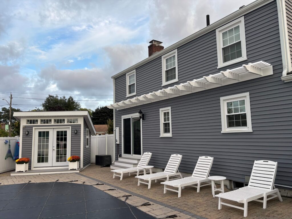 accent wall pergola across the back of a gray blue house