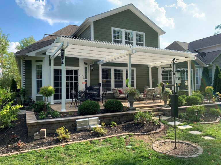 Large patio pergola behind a green house