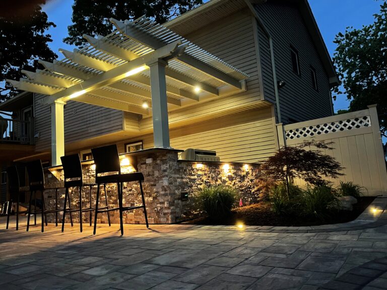 Bar top attached pergola at night lit up with various lighting 