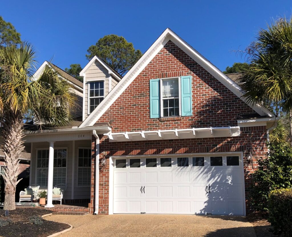 White eyebrow pergola over garage on red brick house