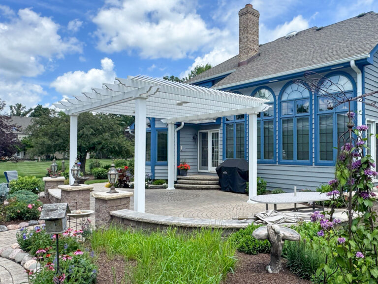 freestanding traditional style white shade pergola on a patio surrounded by a lovely garden