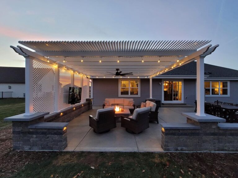 Outdoor Shade pergola at dusk with outdoor fan, outdoor tv, and privacy wall