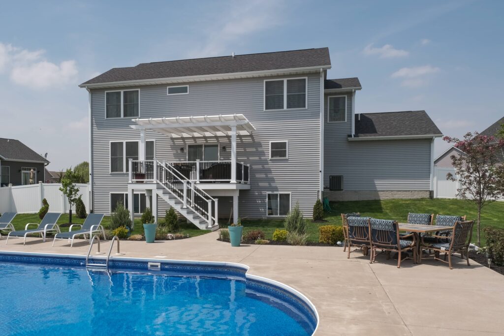 Raised deck with a shade pergola overlooking a backyard pool
