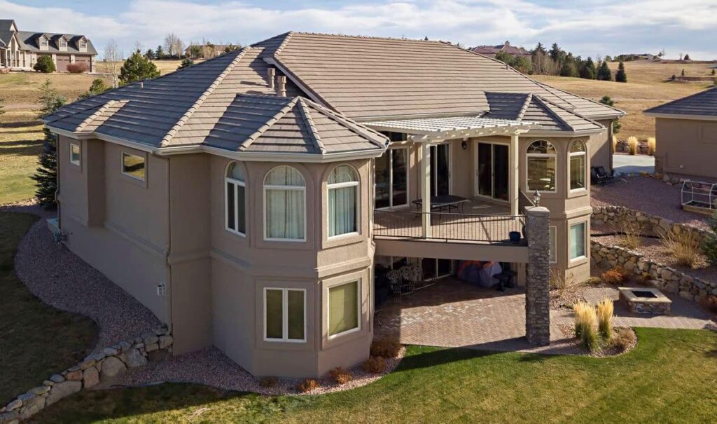 View of an attached pergola on a raised deck of a large home