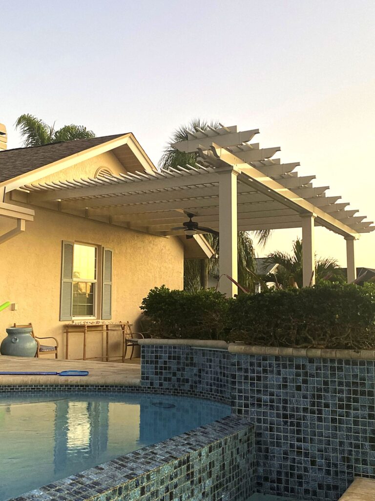 A custom pergola attached to a house with decorative arbor above the beam.