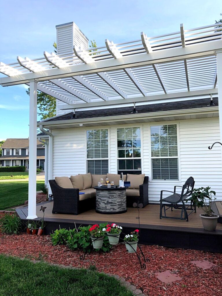 White Vinyl pergola over a deck attached to the roof of a house with Skylift Roof Risers