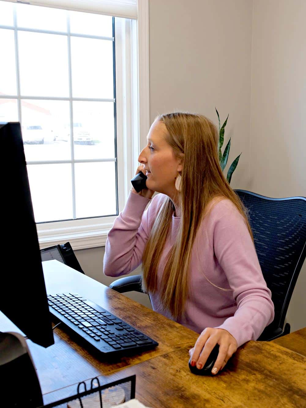 Customer Service agent on the phone with customer while working at a desktop computer