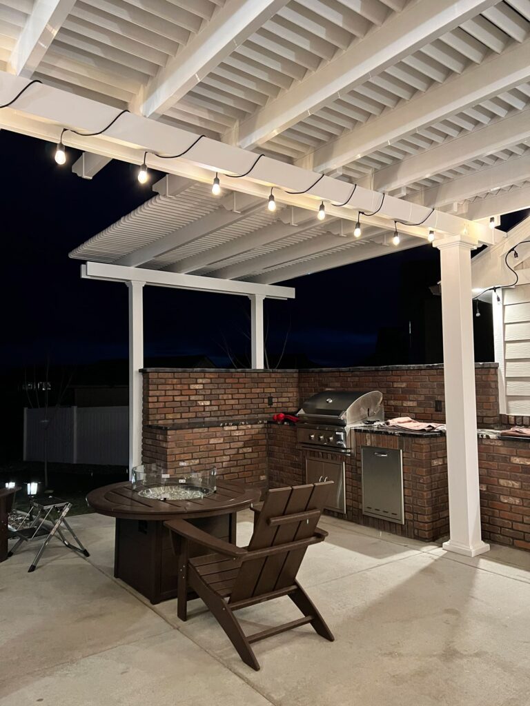L shaped pergola at night lit up with string lights