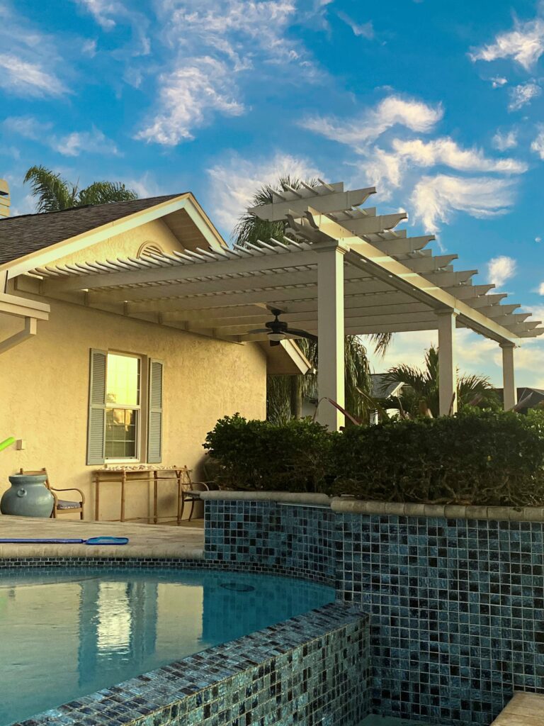 A custom pergola attached to a house with decorative arbor above the beam.