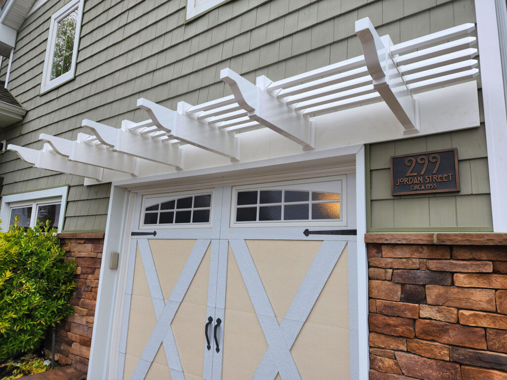 Low view looking up under a white eyebrow pergola over a single car garage