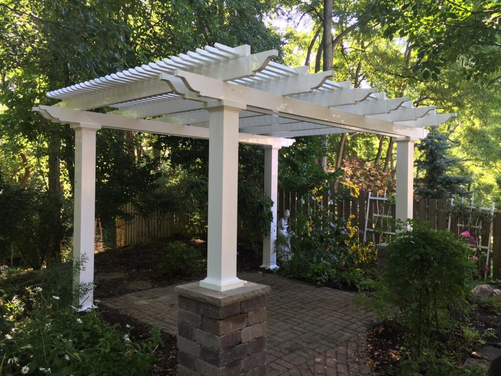 Freestanding pergola with two posts on top of stone pillars over a paver patio