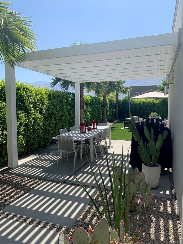 White attached modern pergola over a patio and dining area in a secluded backyard