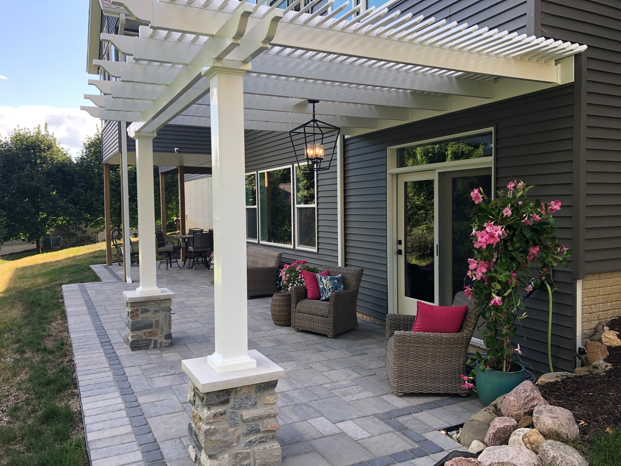 attached patio pergola with small seating area over paver and outdoor chandelier