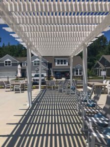 Long narrow pergola over a poolside seating area with 75% shade coverage.